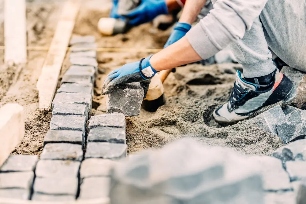 Mason hand-setting granite cobblestones in mortar