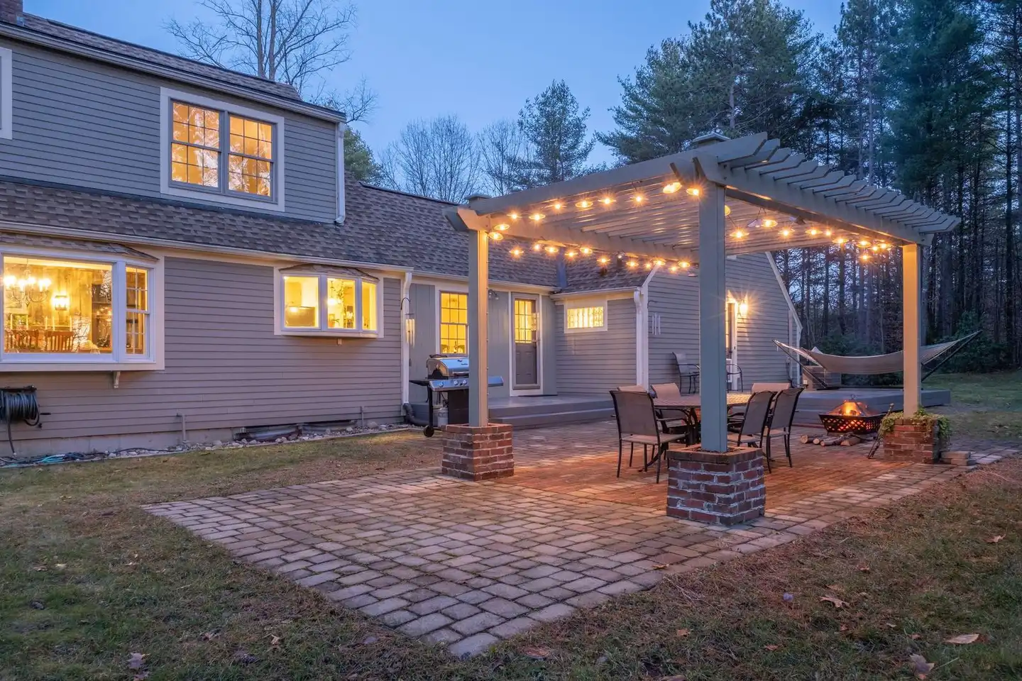 Paver patio with lighting and fire bowl at dusk